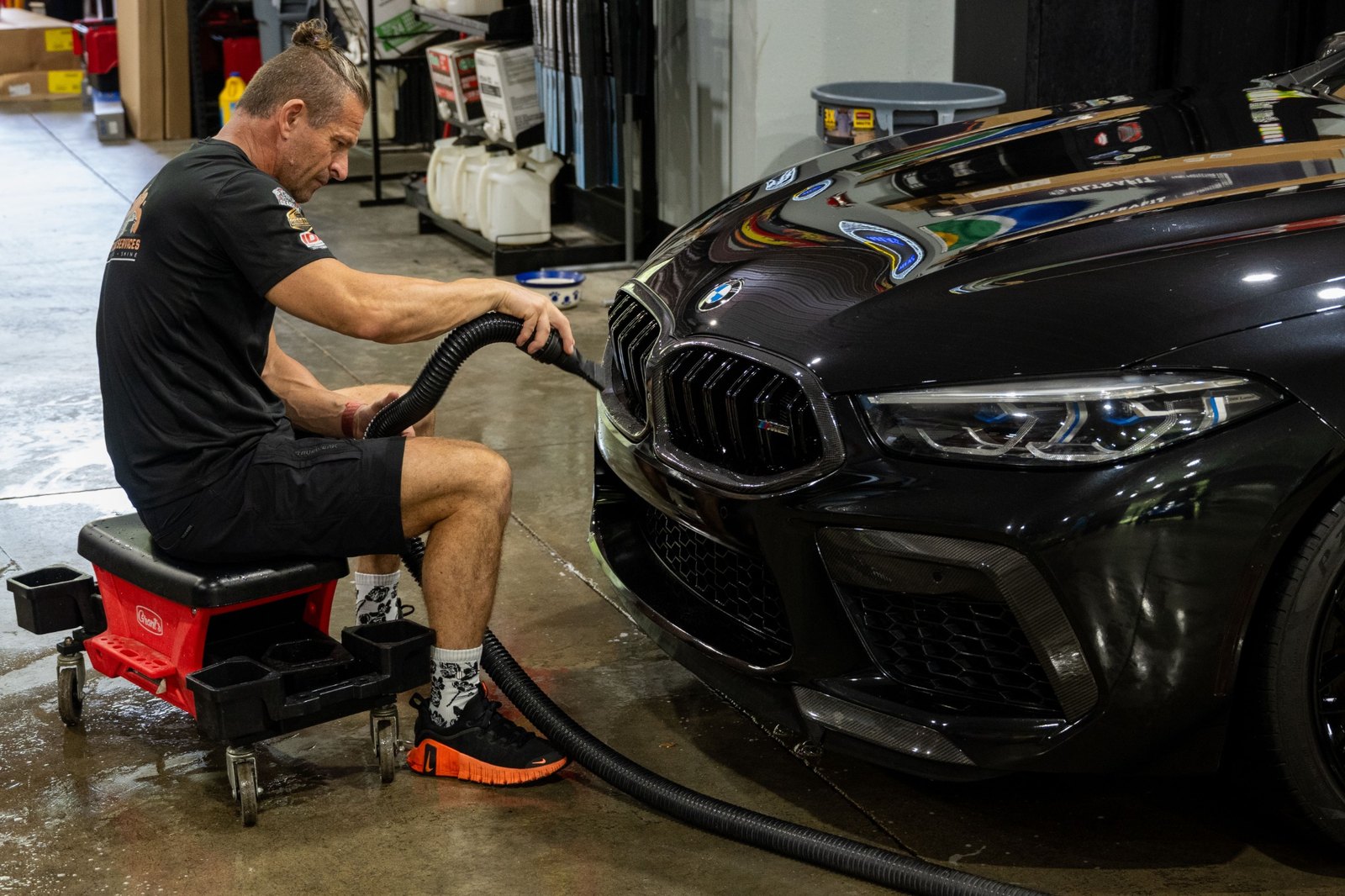 VDS using an air blower around the front of a black BMW during detailing maintenance